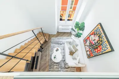 a living room with a white couch and stairs at 5 FODERE - Magnifique Duplex - Port de Nice - Dernier etage in Nice