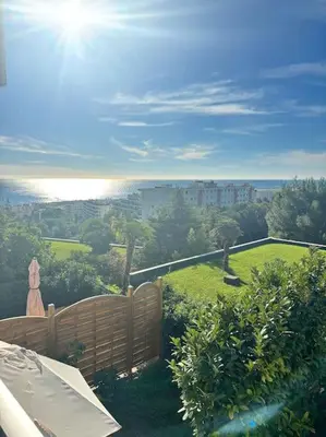 a garden with a fence and a view of a city at Appartement lumineux Vue Mer, Piscine et tennis in Nice