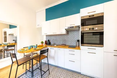 a kitchen with white cabinets and a wooden table at Le Carré d'Or - à 2 min à pied du centre-ville in Nice