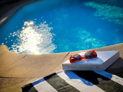 a pair of sunglasses sitting on a book next to a swimming pool at Maison LeFleur in Falicon