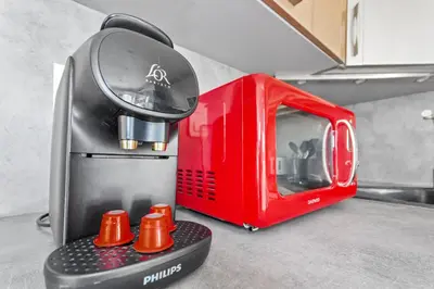 a red toaster sitting on top of a kitchen counter at Le Cosy - Spacious - AC - WIFI - Hippodrome - Racetracks - Hypercentre in Cagnes-sur-Mer