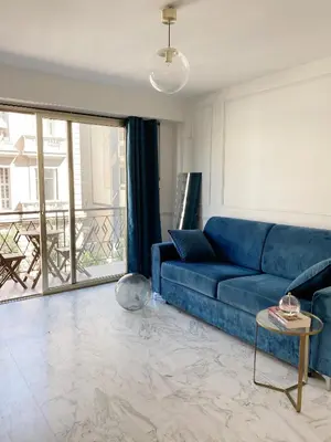 a blue couch in a living room with a large window at Studio Carré Or - Centre Nice 2m à pied de la mer in Nice