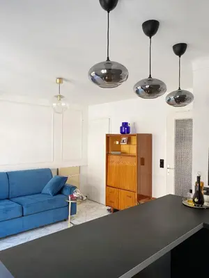 a living room with a blue couch and some lights at Studio Carré Or - Centre Nice 2m à pied de la mer in Nice