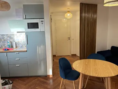 a kitchen with a table and blue chairs in a room at Elégant studio de 25m2 in Saint-Laurent-du-Var