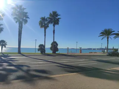 an empty street with palm trees and the ocean at Studio vue mer in Cagnes-sur-Mer