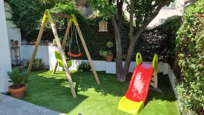 a yard with a swing set on the grass at T3 au calme à deux pas de la mer in Nice