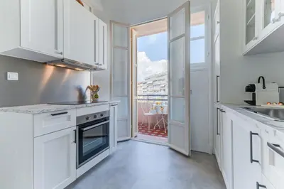 a kitchen with white cabinets and a large window at Elegant Condo with Balconies in the Heart of Nice in Nice