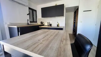a kitchen with brown cabinets and a wooden table at Romantic 1BR Escape with Sun-Rooftop Terrace in Nice