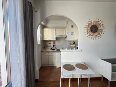 a kitchen with white cabinets and a white table at Studio with large terrace sea view 4th floor in Nice