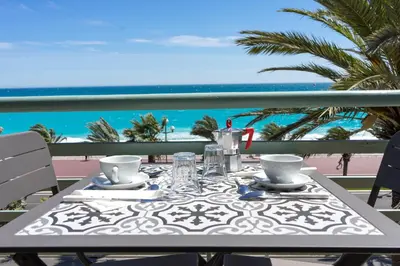 a table on a balcony with a view of the beach at Promenade 2 Pers Vista Mare WiFi AC in Nice