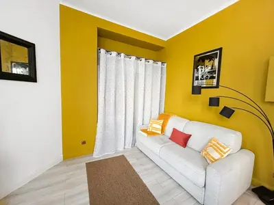 a living room with a white couch and a yellow wall at Charmant studio au coeur de Nice in Nice