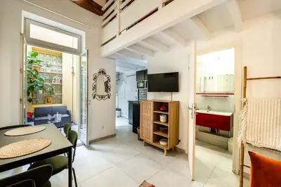 a living room with a table and a kitchen at Jolie duplex avec patio in Nice