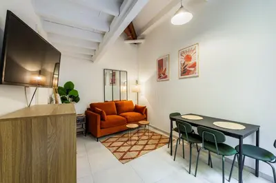 a living room with a couch and a table and chairs at Jolie duplex avec patio in Nice