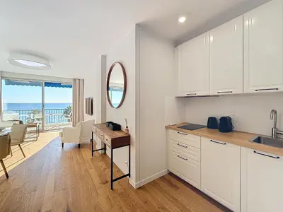a kitchen with white cabinets and a dining room with a table at Seaview Promenade des Anglais 2brs apartment Parking cars 1800 kg max in Nice
