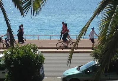 a group of people riding bikes on a road near the ocean at Nice promenade des anglais vue mer in Nice