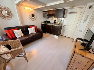 a living room with a brown couch and a kitchen at Tranquil Studio with Mezzanine in Carre dOr in Nice