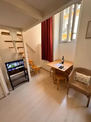 a living room with a table and a television in it at Tranquil Studio with Mezzanine in Carre dOr in Nice