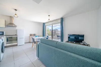 a living room with a blue couch and a kitchen at Magnifique 4 pers,Clim,parking in Nice