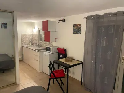 a small kitchen with a table and a microwave at Studio climatisé avec terrasse ombragée dans maison au calme et dans la verdure in Nice