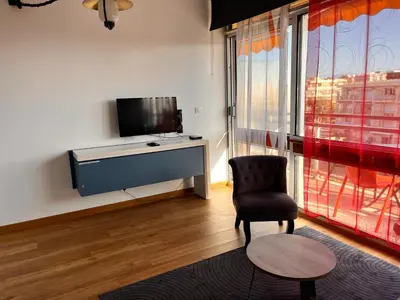 a living room with a tv and a chair at Heliotel Marine Studio avec balcon au 4eme étage à 200m de la mer in Saint-Laurent-du-Var