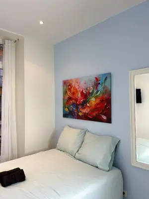 a bedroom with a bed with a painting on the wall at blue sun in Nice