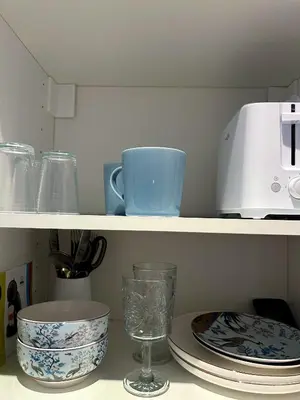 a shelf with cups and plates and a toaster at blue sun in Nice