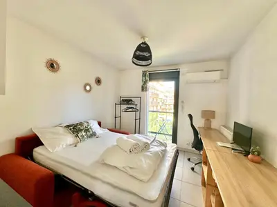 a bedroom with a bed and a desk with a laptop at Studio 600 m de la Promenade des Anglais in Nice