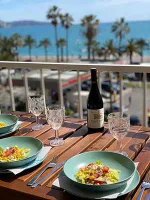 a wooden table with plates of food and a bottle of wine at Nizza-Azur vue mer in Nice