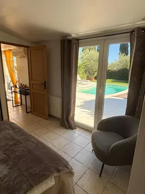 a bedroom with a bed and a chair and a sliding glass door at L'olivier in Gattières