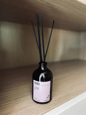 a black bottle with sticks in it sitting on a table at APPARTEMENT en DUPLEX VIEUX NICE in Nice