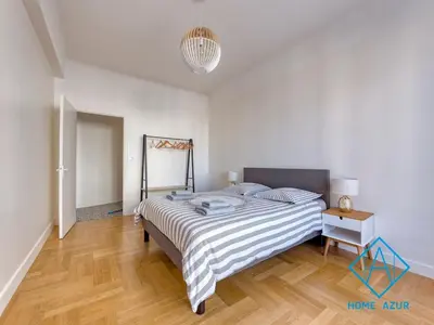 a bedroom with a large bed in a white room at Golden Square in Nice