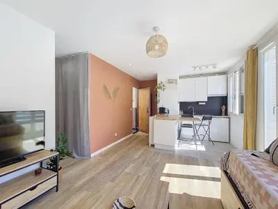 a living room with a couch and a tv and a kitchen at Studio toit terrasse vue mer Sea View in Nice
