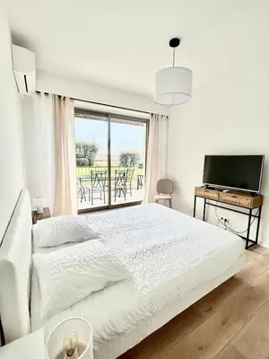 a white bedroom with a bed and a large window at Le Grand Soleil in Nice