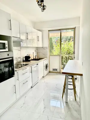 a white kitchen with a table and a window at Le Grand Soleil in Nice