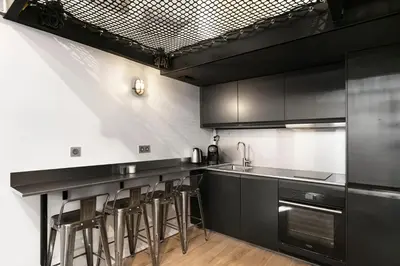 a kitchen with black cabinets and bar stools at Loft Industriel avec Terrasse et Filet Suspendu à Nice Cimiez in Nice
