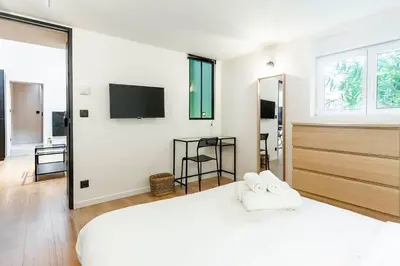 a white bedroom with a large bed and a tv at Loft Spacieux pour 10 personnes avec Terrasse in Nice