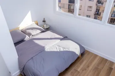 a bed in a white room with two windows at NIce proche mer in Nice