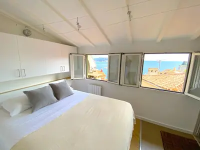 a bedroom with a white bed and two windows at PEARL AP4444 By Riviera Holiday Homes in Villefranche-sur-Mer