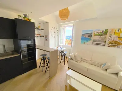 a living room with a white couch and a kitchen at PEARL AP4444 By Riviera Holiday Homes in Villefranche-sur-Mer