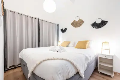 a white bedroom with a large bed and a window at FEEL HOME - Poissonnerie in Nice