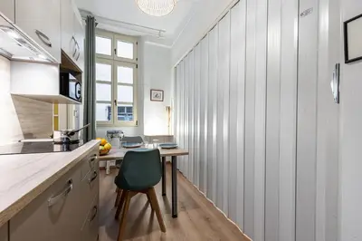 a kitchen with a wooden table and a green chair at FEEL HOME - Poissonnerie in Nice