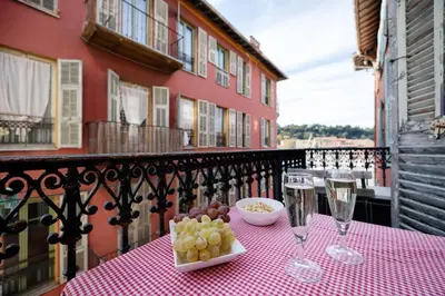 a table with wine glasses and grapes on a balcony at Seabreeze Apt Nice Port in Nice
