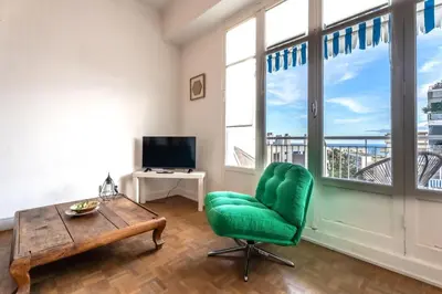 a living room with a green chair and a table and windows at Il Sole e Mare in Nice