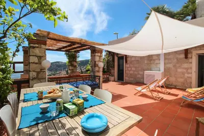 a patio with a table and chairs and a white umbrella at CASA ROSALIE VI4442 By Riviera Holiday Homes in Villefranche-sur-Mer