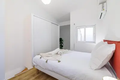 a white bedroom with a large white bed and a window at 1 Bdr Duplex Downtown - AC in Nice