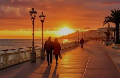 a man and woman walking down a boardwalk at sunset at Studio T1 Centre - Idéal couple & amis - Confort - WIFI - Calme - Climatisation - Coin Terrasse in Nice