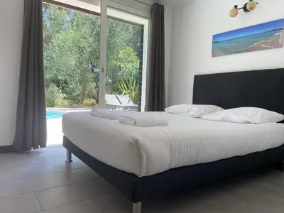 a bedroom with a large bed and a large window at Proche bord de mer, au calme, nature avec piscine in La Gaude