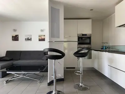 a living room with a couch and two bar stools at Proche bord de mer, au calme, nature avec piscine in La Gaude