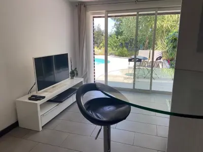a living room with a chair and a tv and a window at Proche bord de mer, au calme, nature avec piscine in La Gaude