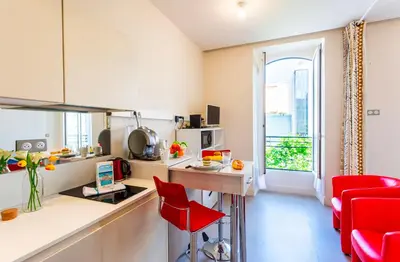 a small kitchen with a red chair and a table at Studio hyper-centre de Nice in Nice